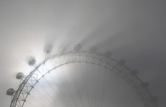 The pods on the London Eye casts shadows against a thick morning fog as the spring sun shine begins to burn it off in central London